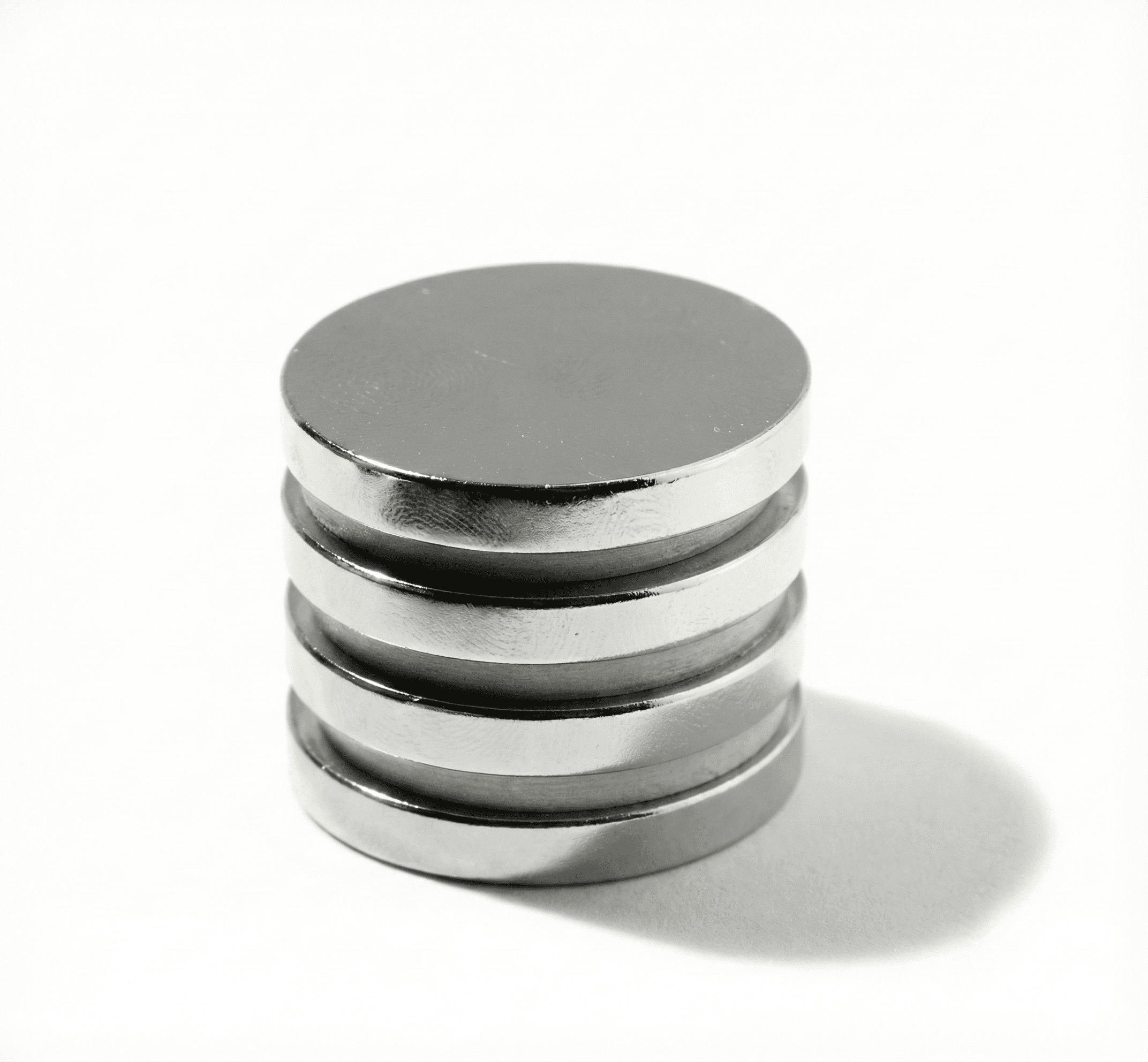 Nickel-plated sintered NdFeB disc magnets stacked on a white surface